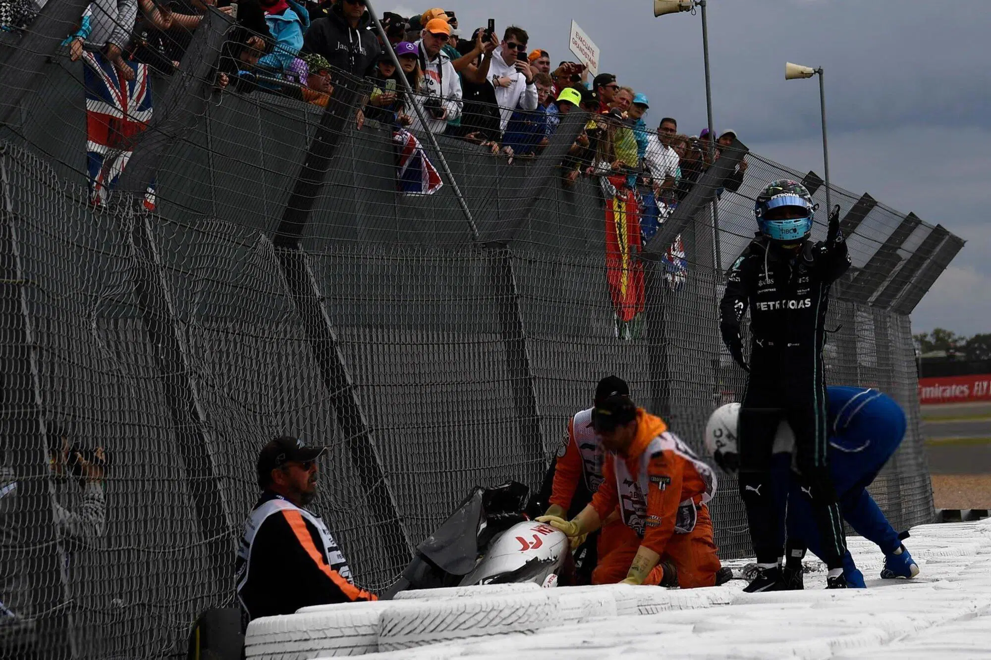 Il casco ancora in testa, in piedi sulle barriere: George Russell "dirige" i lavori dopo l'incidete al primo giro 
