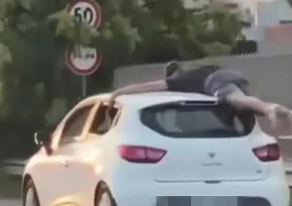 Festeggia la maturit&agrave; aggrappato al tettuccio dell'auto. Da come si comporta, altro che maturo...[VIDEO]