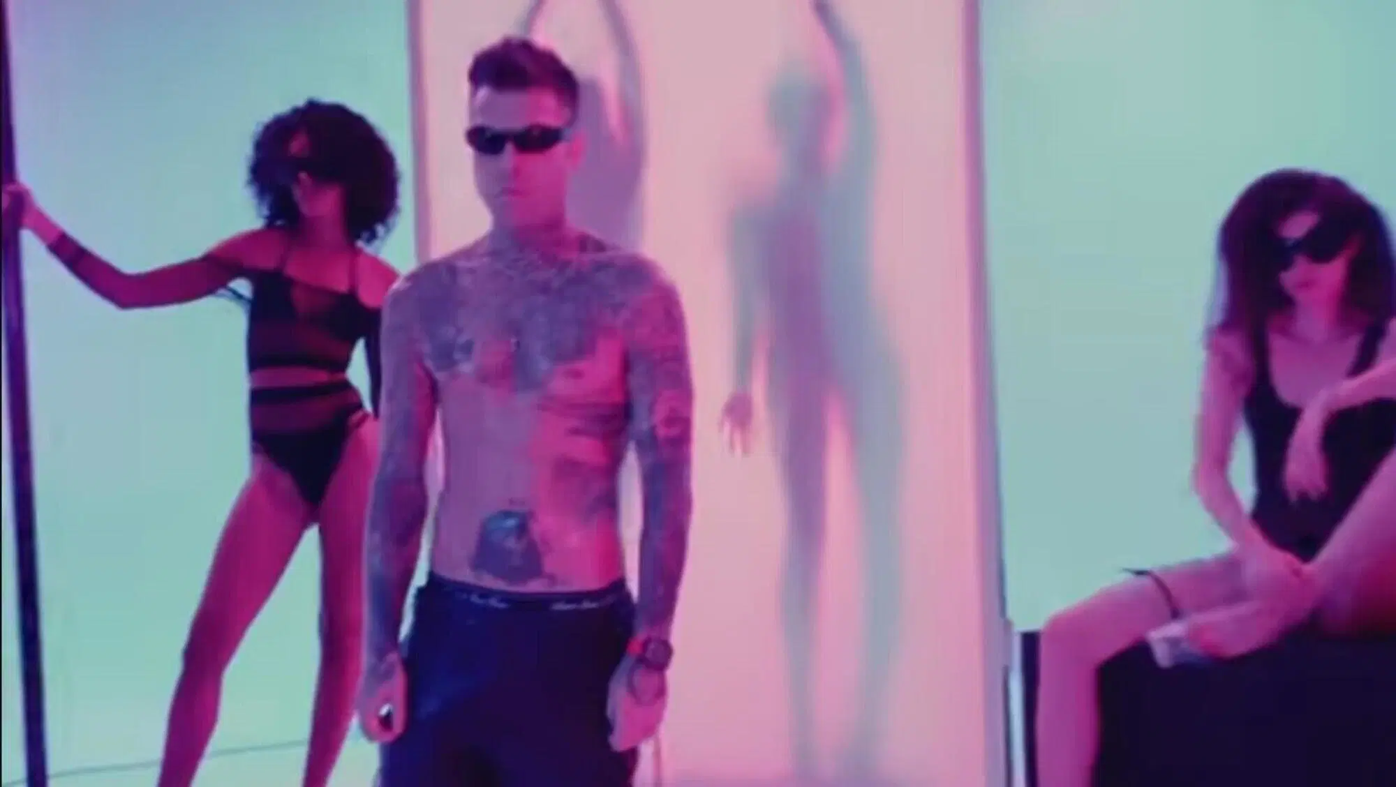 Fedez nel video musicale di Sexy Shop, un po' rigido e immobile, circondato da ragazze in body